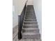 Carpeted stairs with a dark wooden banister, leading to the upper level of the home at 7468 Wellfleet Bay Ave, Las Vegas, NV 89179