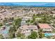 Exceptional aerial shot showcasing a home with a pool, neighborhood pond, and green spaces with city views beyond at 764 Ricota Ct, Henderson, NV 89012