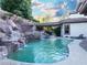 Sparkling pool featuring rock waterfall, outdoor dining, and mature landscaping at 764 Ricota Ct, Henderson, NV 89012