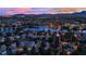 Sunset aerial of community with a lake, showcasing homes, city lights, and distant mountains at 7837 Sea Rock Rd, Las Vegas, NV 89128