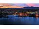 Panoramic aerial view of a lakeside community featuring a serene lake, palm trees, and city lights at dusk at 7837 Sea Rock Rd, Las Vegas, NV 89128