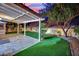 Inviting covered patio with stone flooring, artificial turf, and mature trees creating a private outdoor space at 7837 Sea Rock Rd, Las Vegas, NV 89128