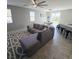 Open-concept living space with tile flooring, a ceiling fan, and gray L-shaped sofa at 7990 Formitch Ct, Las Vegas, NV 89166