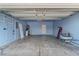 Clean garage with blue walls and ceiling, concrete floor, overhead shelving, and interior door at 8509 W Rochelle Ave, Las Vegas, NV 89147