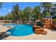 Beautiful swimming pool area with rock waterfall and basketball hoop and lush landscaping at 1016 Sable Mist Ct, Las Vegas, NV 89144