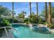 Beautiful pool and spa surrounded by lush landscaping, mature palm trees and a clear sky at 10320 Luxembourg Ave, Las Vegas, NV 89145