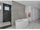 Modern bathroom featuring a soaking tub, walk-in shower, and decorative tile accent wall at 10752 Patina Hills Ct, Las Vegas, NV 89135