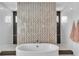 Modern bathroom featuring a soaking tub, walk-in showers and decorative tile accent wall at 10752 Patina Hills Ct, Las Vegas, NV 89135