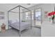 Modern bedroom featuring a four poster bed, outside patio and white walls at 10752 Patina Hills Ct, Las Vegas, NV 89135
