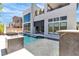Backyard pool with a fire feature, lounge chairs, and a modern home exterior, creating a luxurious outdoor space at 10752 Patina Hills Ct, Las Vegas, NV 89135