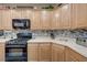 Close-up of kitchen featuring light wood cabinets, black appliances, and modern backsplash at 1076 Crescent Falls St, Henderson, NV 89011