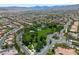 Expansive aerial view of a Primary-planned community with lush green spaces, a central park, and views of distant mountains at 11253 Revelry Ln, Las Vegas, NV 89138