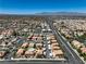 Extensive aerial view showcases homes, a long road, businesses, and distant mountains under a clear sky at 1201 N Buffalo Dr # 202, Las Vegas, NV 89128