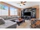Spacious living room with a comfortable gray sofa, large windows, and a custom entertainment center at 2366 Brockton Way, Henderson, NV 89074