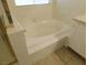 Close up on a large white bathtub with tile surround and a shower with gold trim at 241 Honeywood St, Henderson, NV 89074