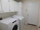 Well-lit laundry room featuring modern washer and dryer, white cabinetry and tile flooring at 241 Honeywood St, Henderson, NV 89074