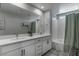 Bright bathroom featuring double sinks, a large mirror, and a tub-shower combination with a gray curtain at 2530 Catallo St, Henderson, NV 89044