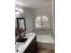 Bathroom featuring white vanity with dual sinks, soaking tub with elegant arched window, and modern fixtures at 332 Dockside Ct, Las Vegas, NV 89145