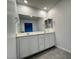 This bathroom features double sinks with white cabinets, a large mirror, and gray tile floors at 3493 Arcadian King Ave, Las Vegas, NV 89106