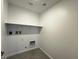 A simple laundry room with tile floors, utility hook ups, and a shelf for storage at 3493 Arcadian King Ave, Las Vegas, NV 89106