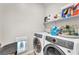 Well-equipped laundry room with modern washer and dryer units and convenient shelving for storage at 4332 Stardusk Falls Ave, North Las Vegas, NV 89084