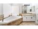 Bathroom with a luxurious jacuzzi tub, neutral tile surround, modern fixtures, and natural light from the window at 5225 Sandy Cactus Ln, Las Vegas, NV 89149