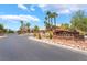 Gated community entrance with desert landscaping, mature trees, and stone signage at 5225 Sandy Cactus Ln, Las Vegas, NV 89149