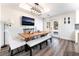 Bright dining area features a modern chandelier, wood table with bench and chairs, and dark wood-look floors at 5225 Sandy Cactus Ln, Las Vegas, NV 89149