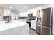 Bright kitchen boasts white cabinets, stainless steel appliances, gray backsplash, and a large island with quartz countertops at 5225 Sandy Cactus Ln, Las Vegas, NV 89149