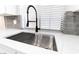Close-up of a stainless steel kitchen sink with a gray tile backsplash and a window with blinds at 5225 Sandy Cactus Ln, Las Vegas, NV 89149
