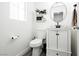 Stylish half bath featuring white vanity with black hardware, modern round mirror, and wood-look tile flooring at 551 Swiss Cottage Ave, Las Vegas, NV 89178
