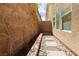 Narrow side yard featuring a stone pathway, decorative rock bed, and a vine-covered wall at 551 Swiss Cottage Ave, Las Vegas, NV 89178