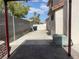 Backyard concrete patio and long driveway featuring an A/C unit, trash cans, and block walls at 6043 Cape Clairmont Ct, North Las Vegas, NV 89031