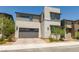 Modern two-story home featuring stone accents, a paved driveway, and a gray two-car garage at 6927 Desert Finch St, North Las Vegas, NV 89084