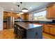 A modern kitchen features wood cabinets, stainless steel appliances, and a large gray island with chairs at 6927 Desert Finch St, North Las Vegas, NV 89084