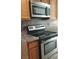 Kitchen with stainless steel oven range with microwave above, wood cabinets, and laminate countertop at 728 Apple Tree Ct, Henderson, NV 89014