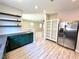 Kitchen with floating shelves, stainless steel refrigerator, unique green cabinets, and an open view to the living room at 7537 Brisa Del Mar Ave, Las Vegas, NV 89179