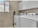 Efficient laundry room with modern appliances, overhead cabinets and natural light at 7720 Leavorite Dr, Las Vegas, NV 89128