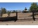 View of the home through a chain link fence with trees and desert landscaping at 871 Buol Rd, Pahrump, NV 89048