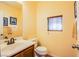 Cozy half bath with a wood vanity, white toilet, and window with wood blinds at 9022 Sosa Creek Ave, Las Vegas, NV 89149