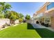 A backyard with artificial grass, a covered patio, and a view of the home's windows at 1013 Corsica Ln, Las Vegas, NV 89144