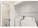 A laundry room featuring white washer and dryer units, shelving, and access to a half bath at 10437 Coyote Cub Ave, Las Vegas, NV 89129