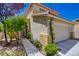 Inviting front entrance with a paved walkway, lush greenery, a well-manicured lawn, and a two-car garage, enhancing curb appeal at 10645 Lace Vine Arbor Ave, Las Vegas, NV 89144