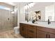 Bathroom featuring double sinks, wood cabinets, a large mirror, and a tiled shower at 11756 Emerald Lake Ave, Las Vegas, NV 89138