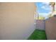 Exterior shot featuring wall with a small patch of grass and view of a light tan structure at 11756 Emerald Lake Ave, Las Vegas, NV 89138