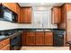 Kitchen area featuring black appliances, wood cabinets and a black countertop at 11900 Calle De Sol Dr, Las Vegas, NV 89138