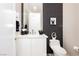 Modern bathroom with a sleek white vanity, black tiled accent wall and modern toilet at 12382 Tudor Arch Dr, Las Vegas, NV 89138