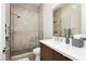 Modern bathroom with sleek white countertop, wood vanity, and walk-in shower at 12382 Tudor Arch Dr, Las Vegas, NV 89138