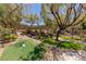 Lush backyard featuring a putting green, mature trees, and a shaded pergola area at 17 Winding Rd, Henderson, NV 89052