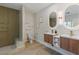 Bright bathroom with dual sinks, wood cabinets, modern mirrors, and large glass shower at 17 Winding Rd, Henderson, NV 89052